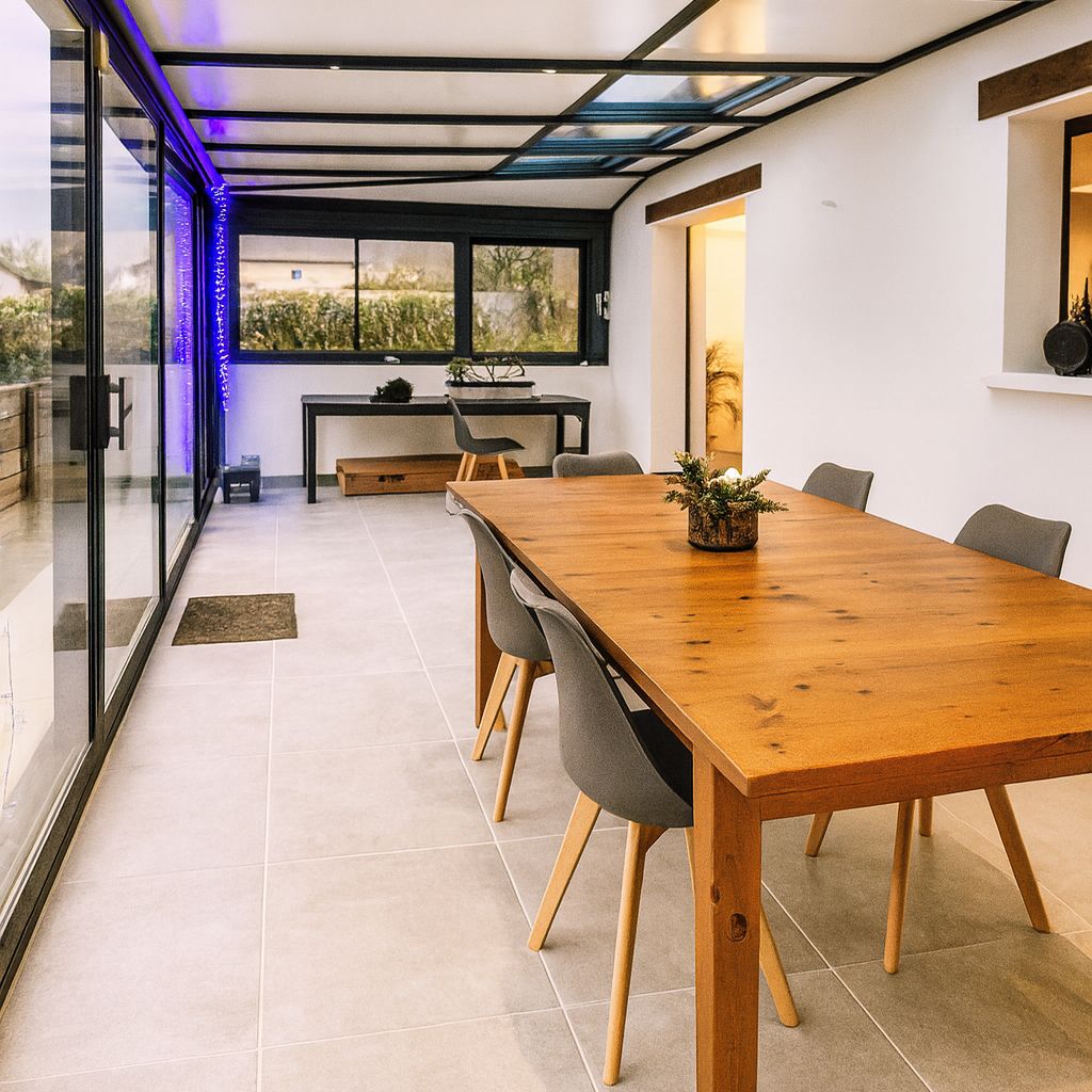 Véranda livrée par Pégase après rénovation complète : carrelage, mobilier bois, éclairage LED